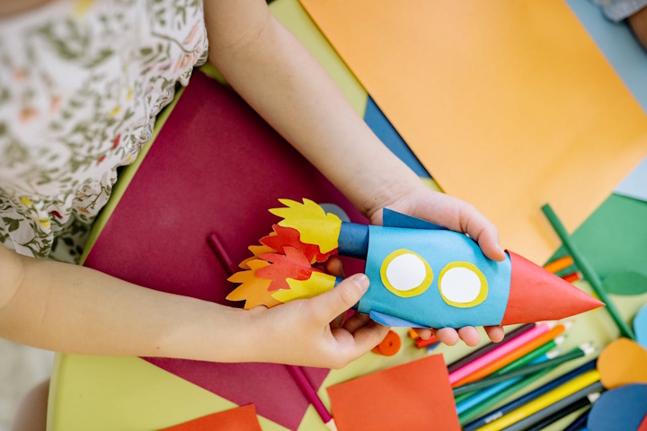 Child making a space rocket from coloured paper
